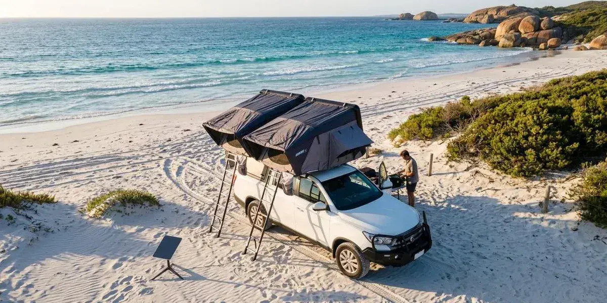 Aerial view of a 4WD camper parked at a beachside campsite in Western Australia with Starlink dish set up and ocean waves visible in the distance