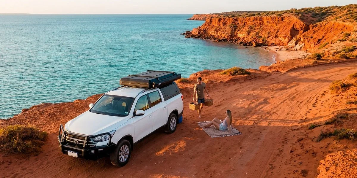 Crystal clear turquoise water meeting red sandstone cliffs at Francois Peron National Park in Shark Bay Western Australia